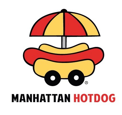 Smiling young woman with curly hair sitting at a laptop, in front of a teal wall.