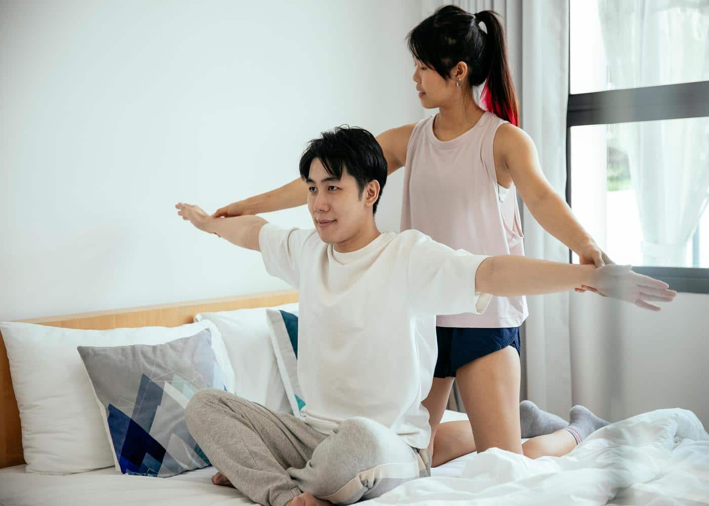 Woman guiding man through an exercise in bed