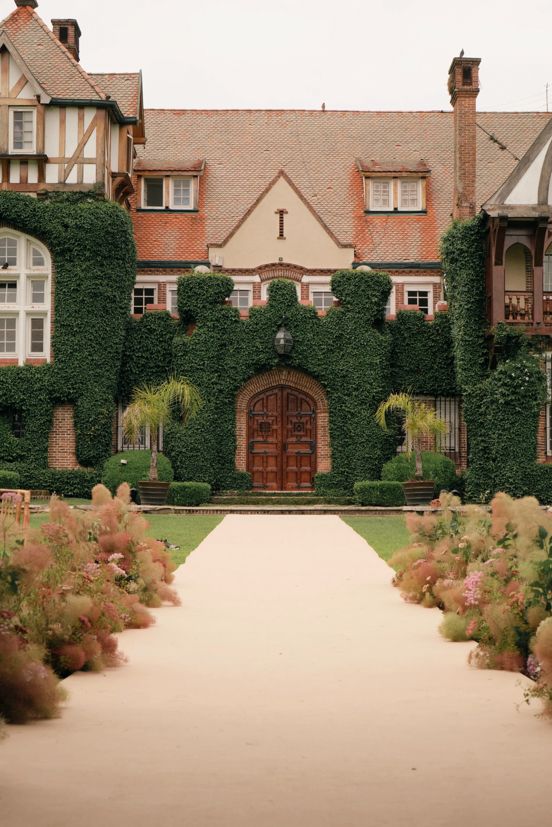 Perspectiva del altar en Villa María con alfombra beige enmarcada por flores silvestres hacia fachada histórica.
