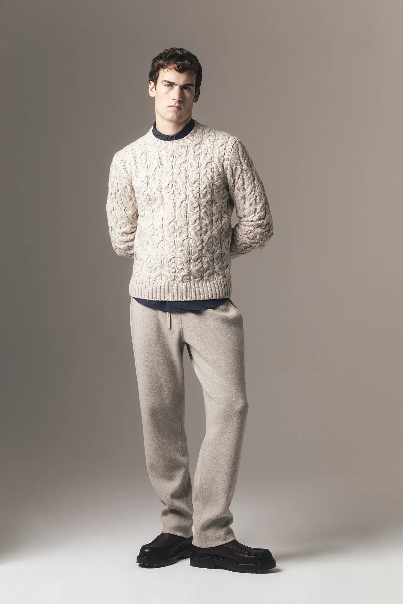 Man wearing beige cable-knit cashmere sweater over navy shirt with light trousers – Aida Barni FW25/26.