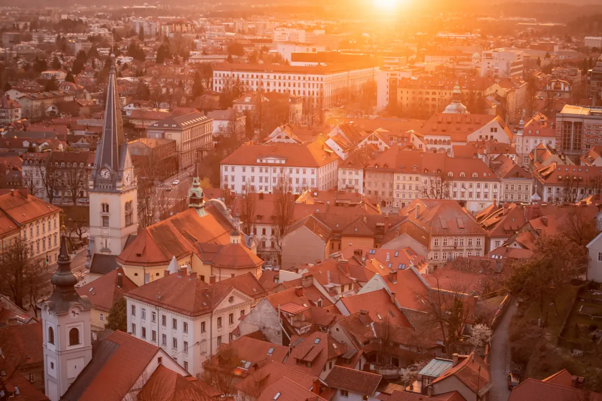 Sunset over Ljubljana city center casting golden light over the orange roofs.