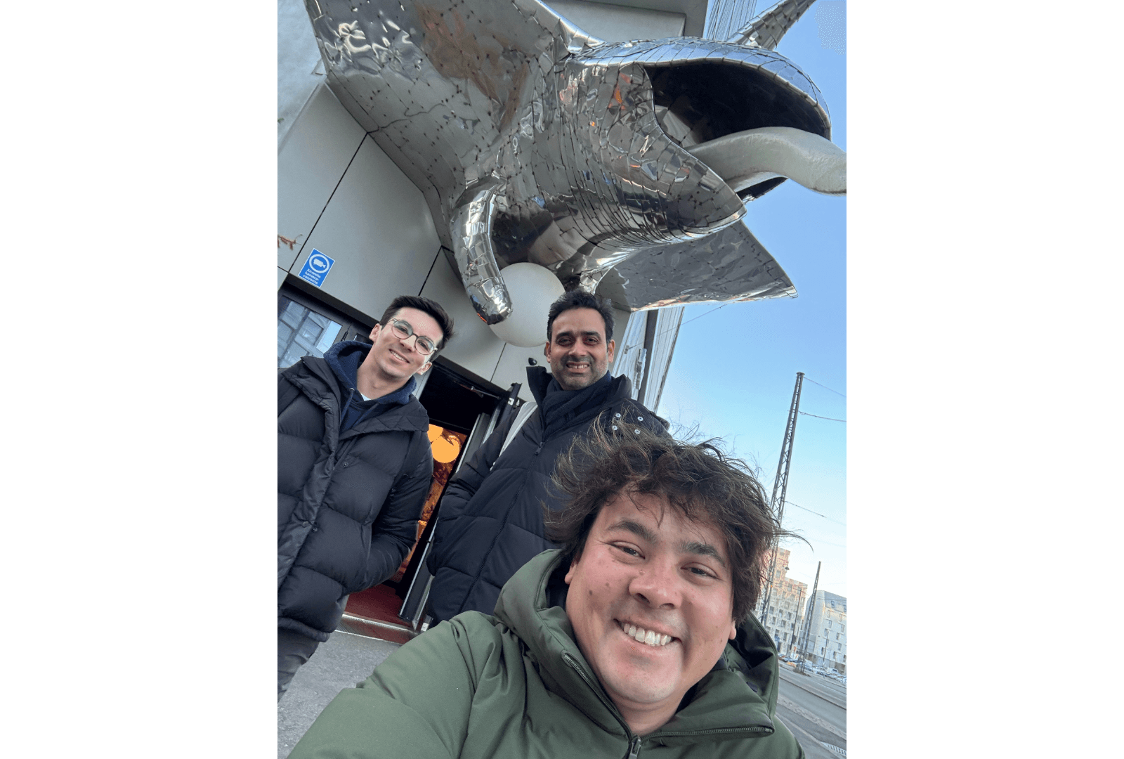 Sociability team members in front of Hotel AX, Helsinki. A large animal sculpture with a mirrored surface looms over the hotel entrance.