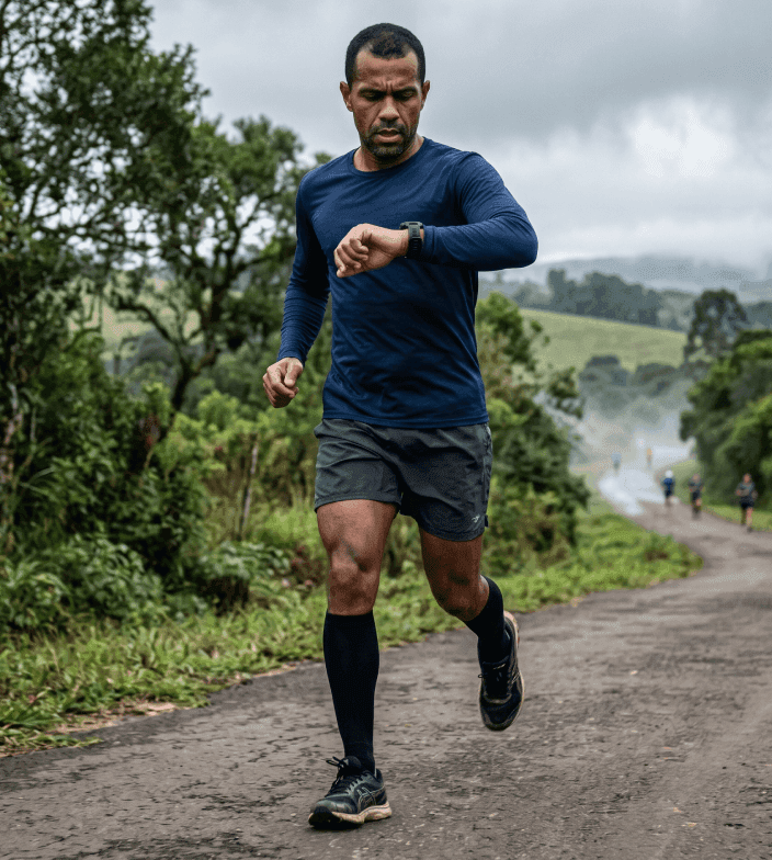 Corredor olhando o relógio durante treino para controlar o ritmo e evitar quebrar na corrida.