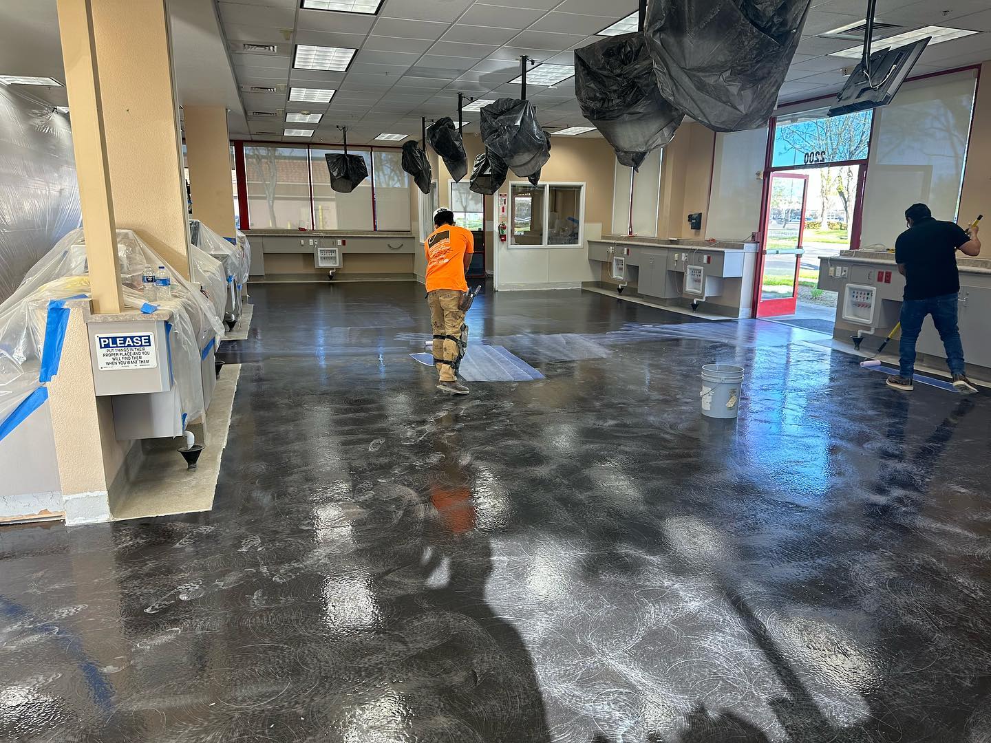 Crew working sealer out to the edges of a commercial service floor