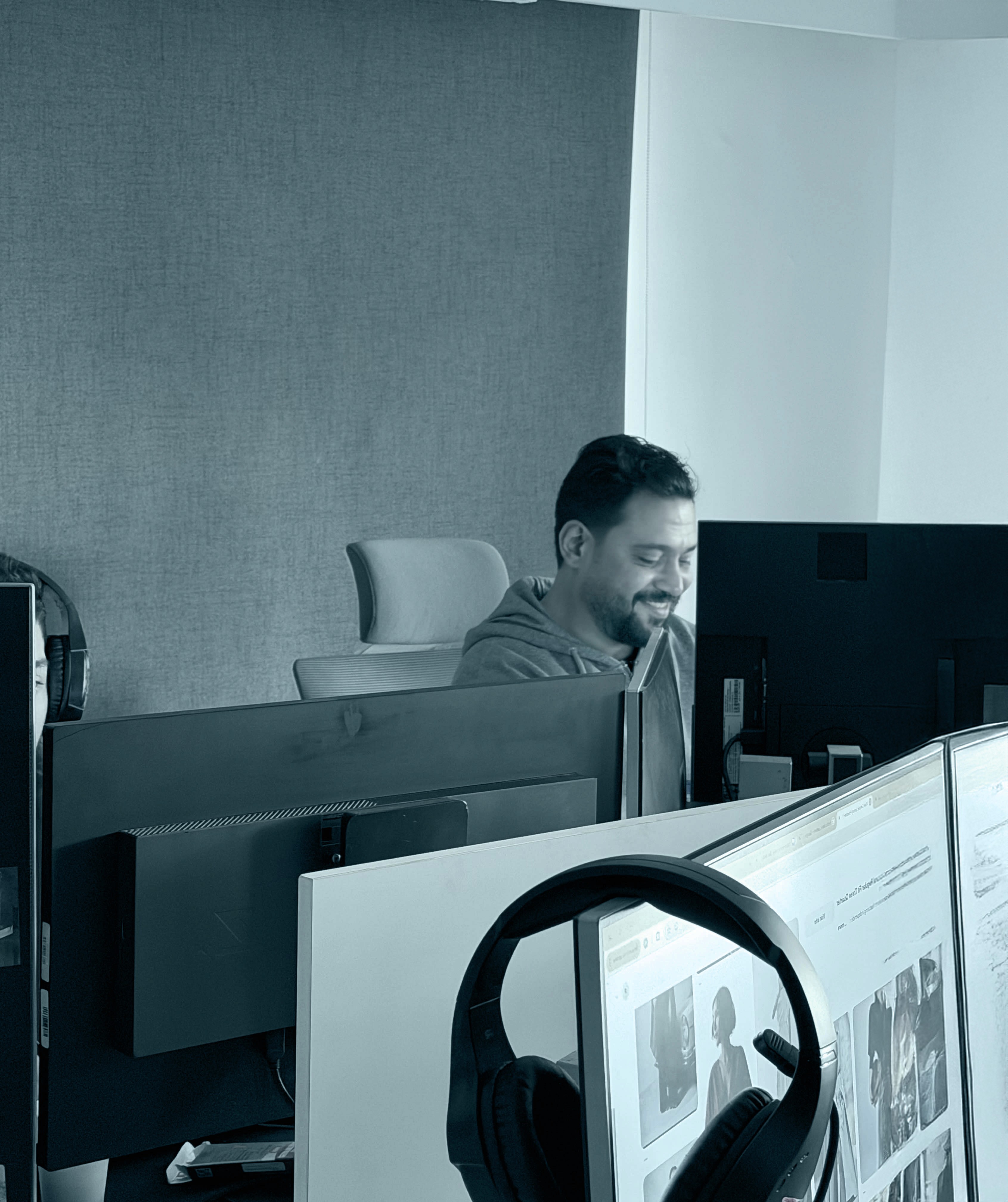Black and white photo of two people looking at a computer screen with papers on wall
