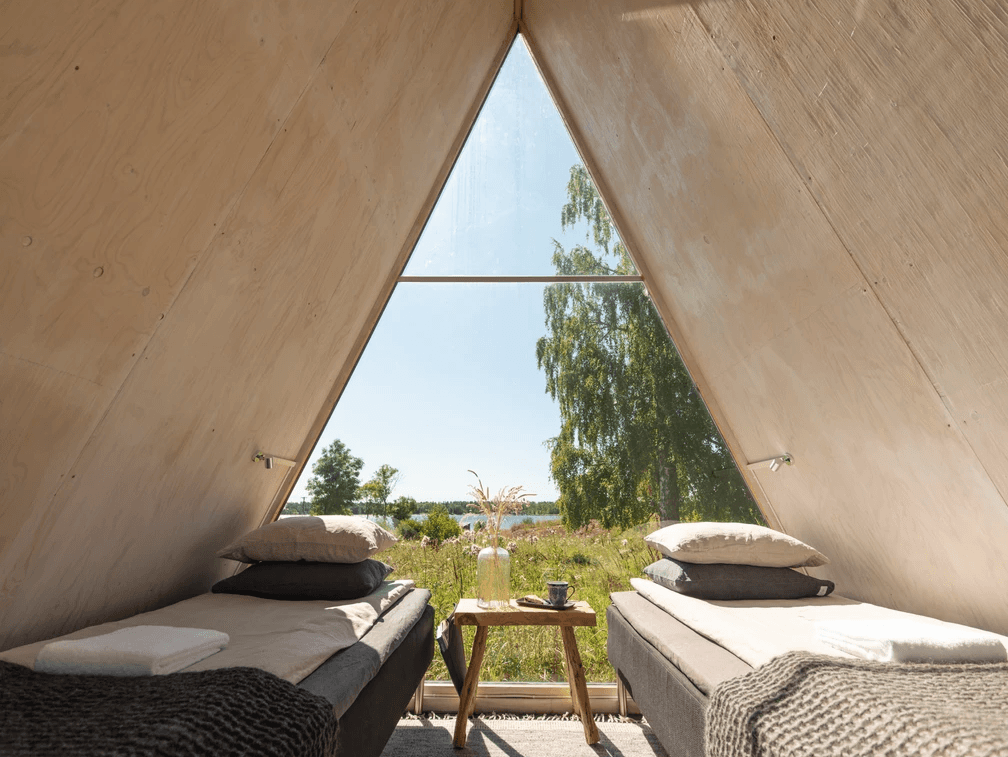 A triangular cabin with two beds looking out into nature