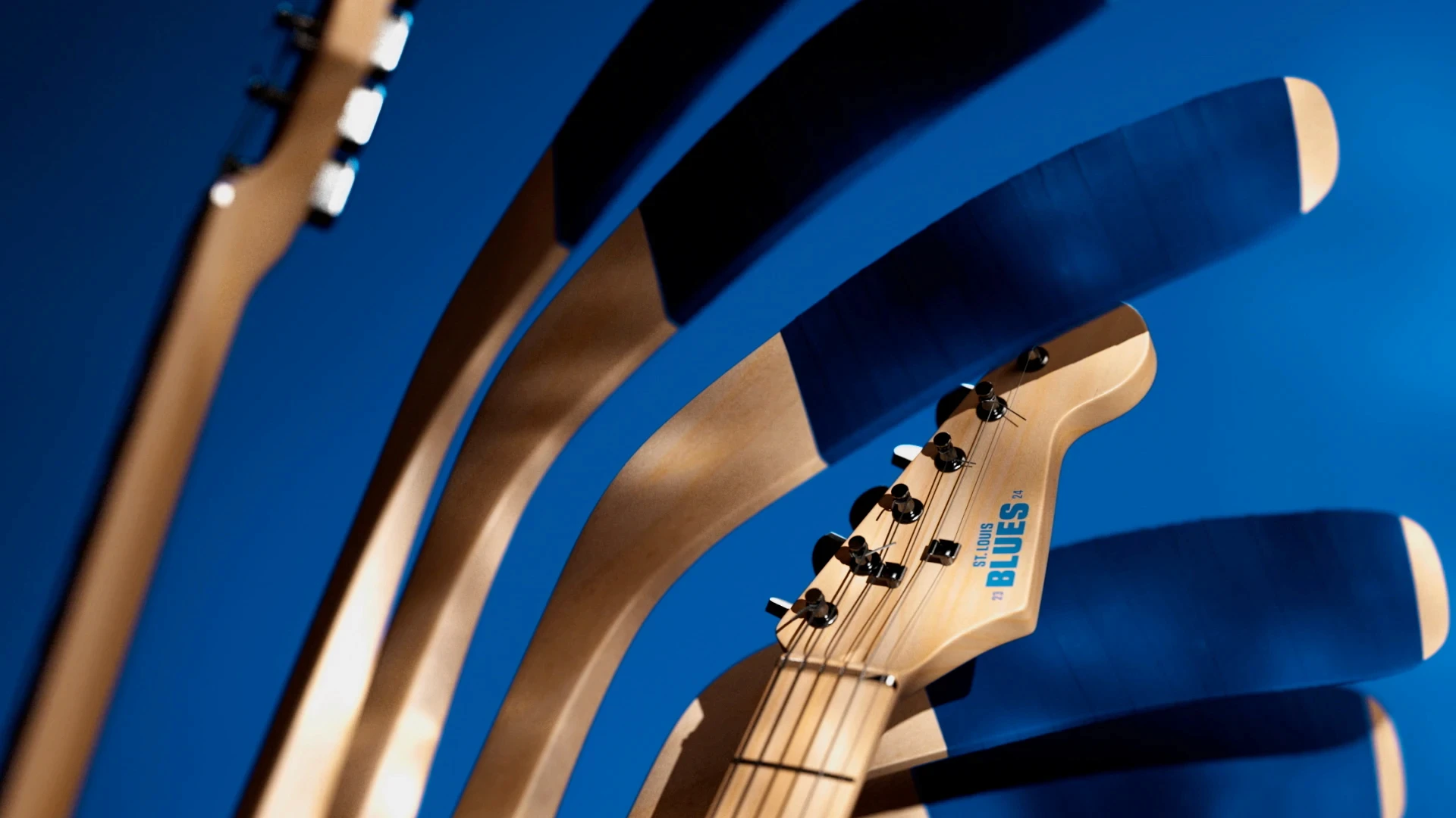 Close-up of St. Louis Blues electric guitar neck repeated in an abstract arc pattern on a blue background