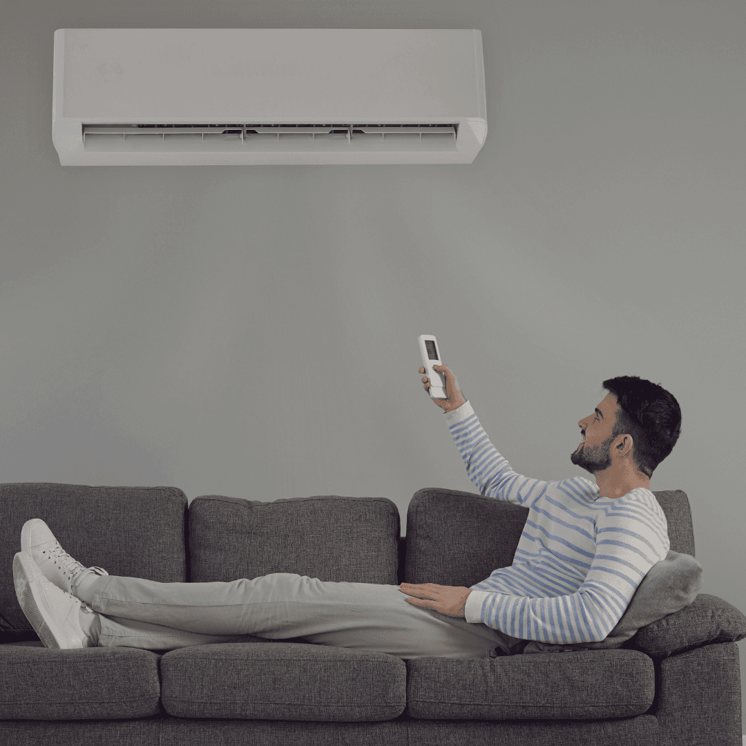 man ligt op de bank met airco afstandsbediening in de hand