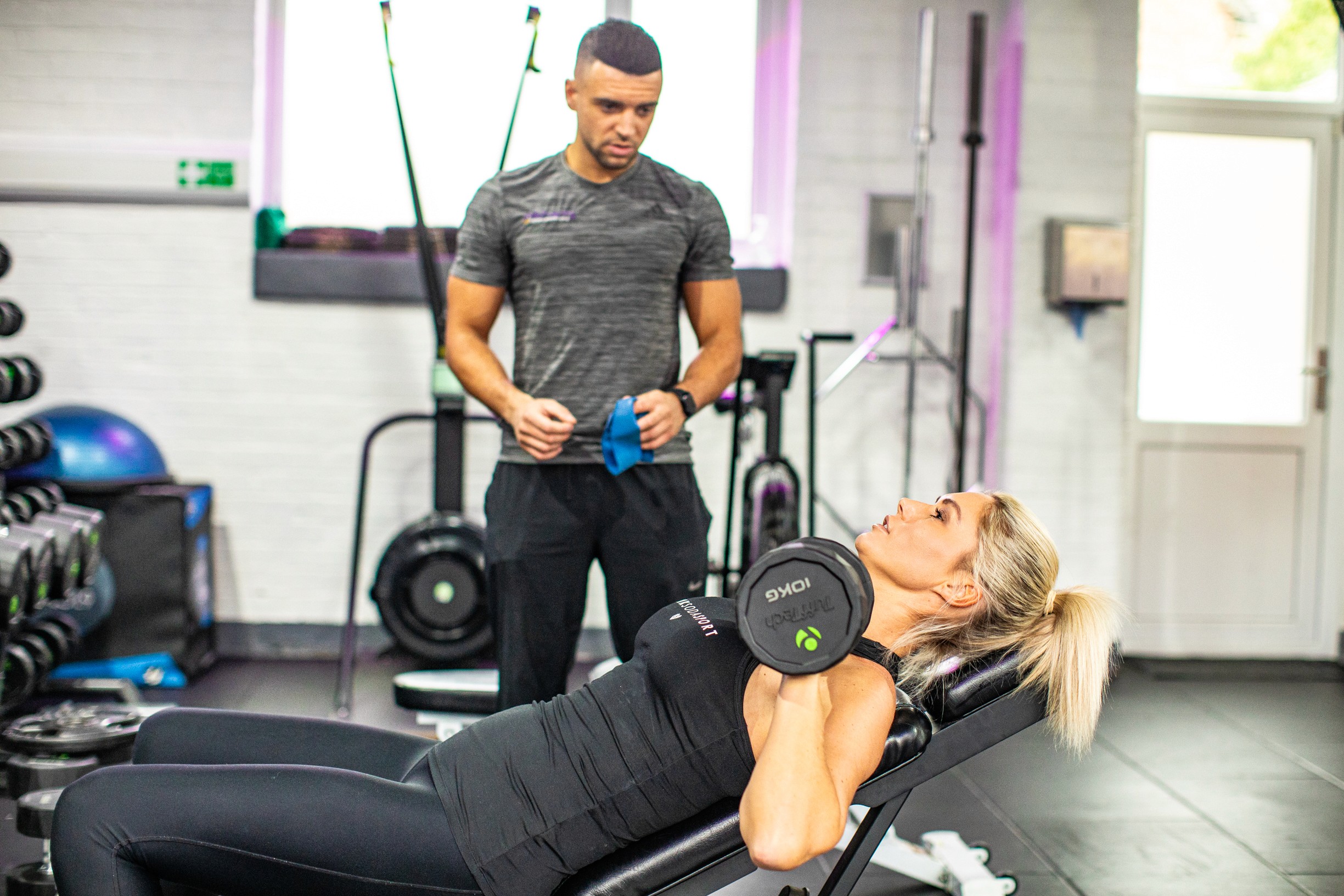 A personal coach is smiling with his arms crossed, wearing a black