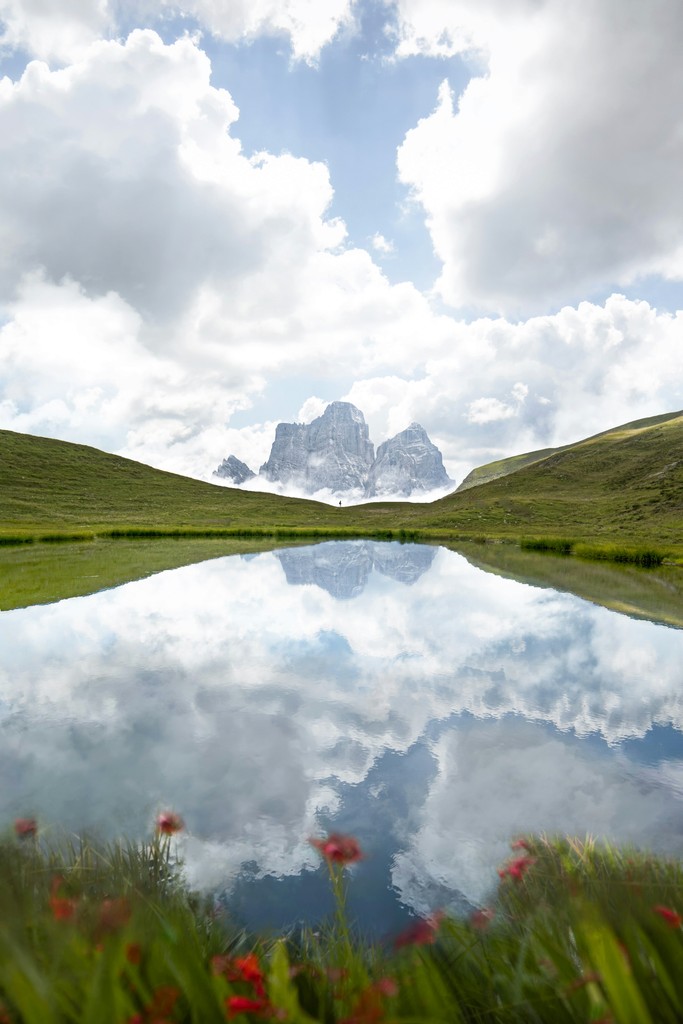 A calm pond surrounded by grass with mountains in the distance