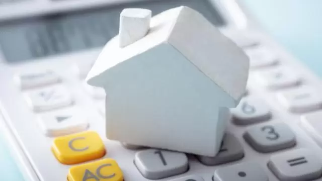 a small home figurine on top of a calculator