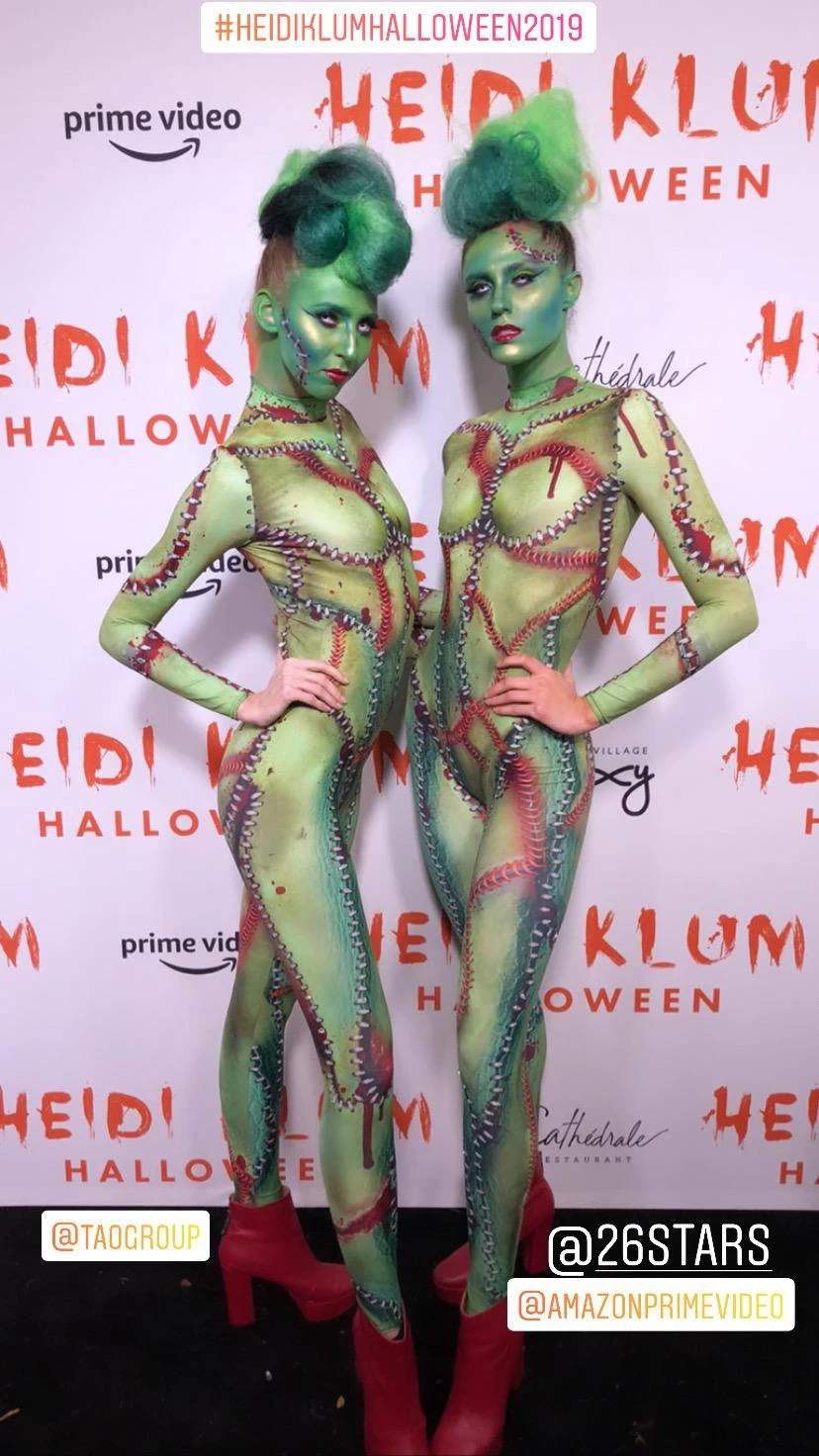 Two body-painted green alien performers at Heidi Klum's Halloween party