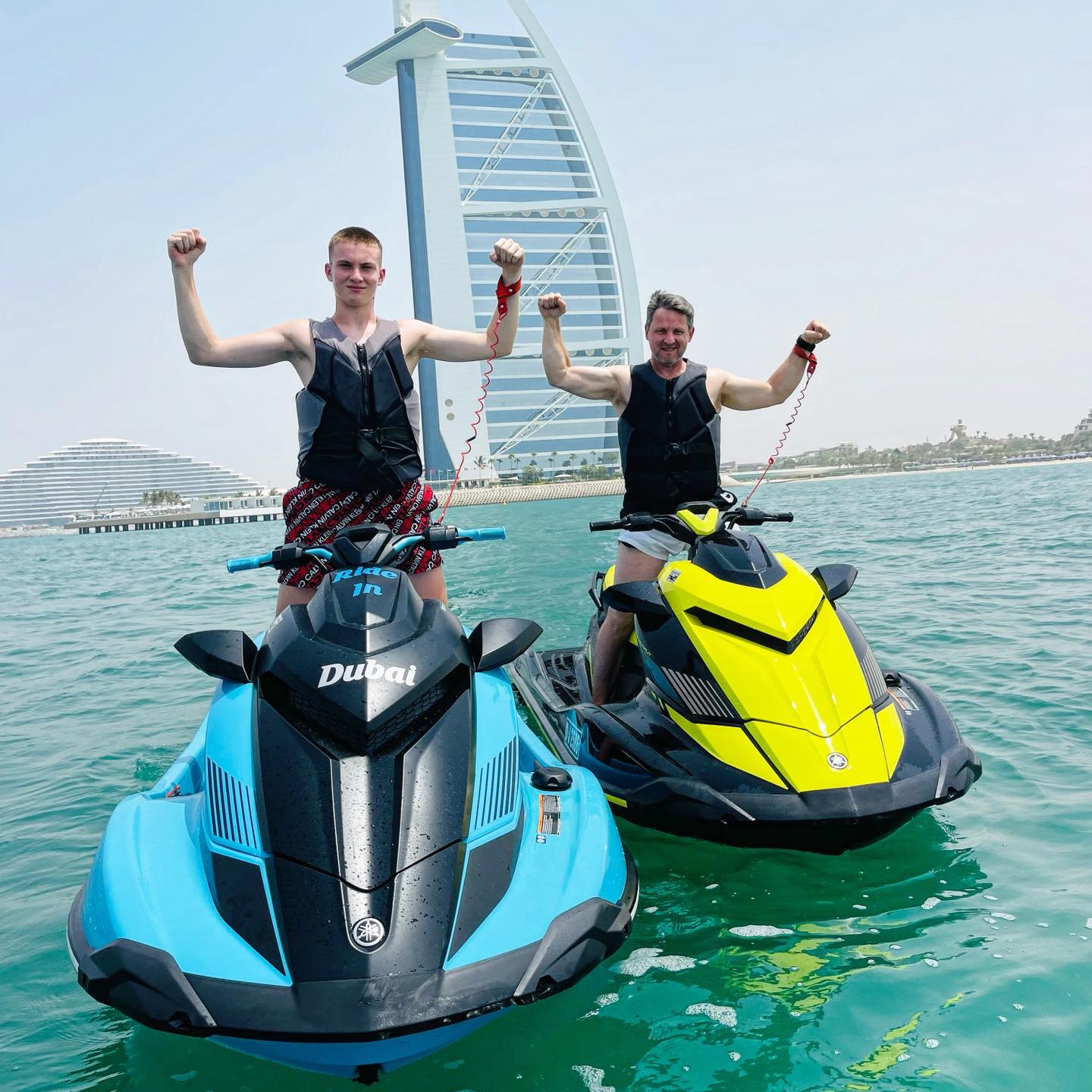 Two riders on their jet skis with safety keys attached to their wrists.