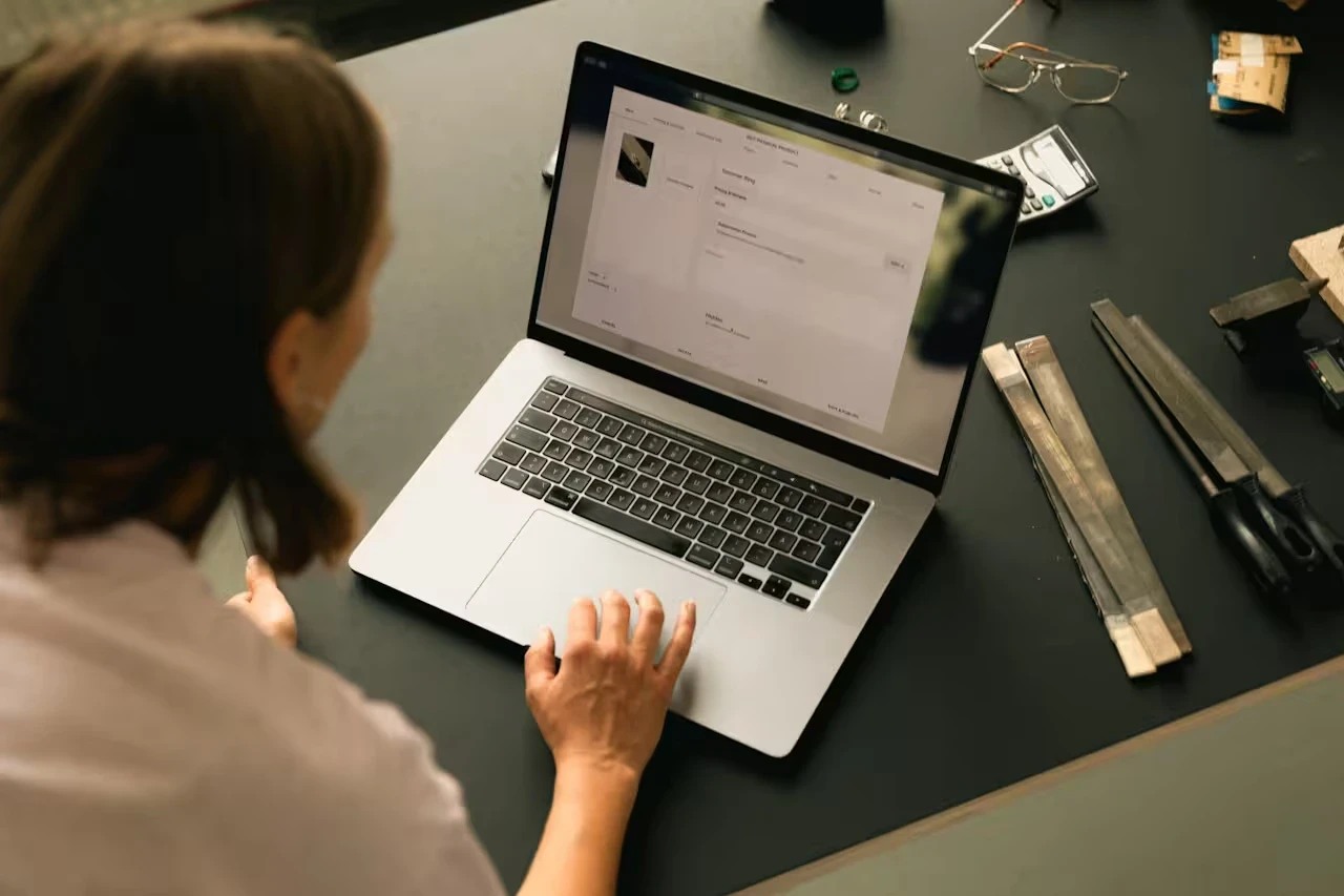 A person views a product detail page on a laptop while seated at a workbench with tools nearby.