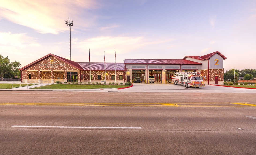 Street view of City of Deer Park Fire Station 2 with brick facade and tower at dusk, by Martinez Architects
