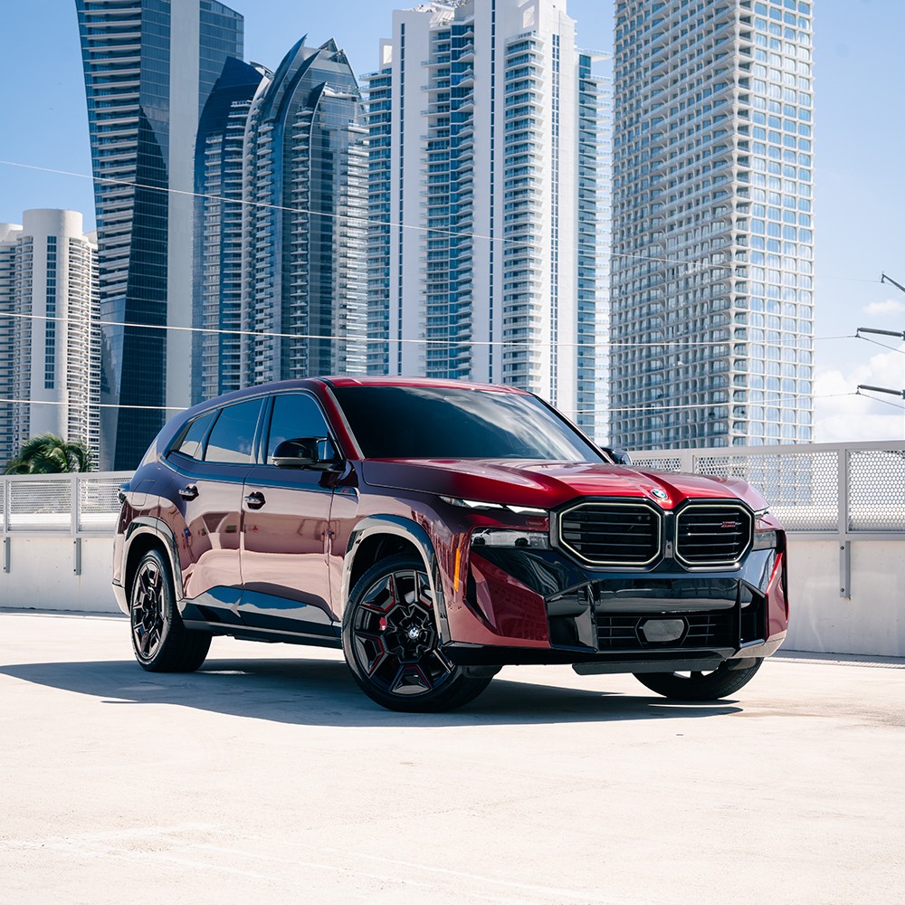 Front 3/4 view of a red BMW XM Label Red luxury SUV rental in Miami, showcasing its bold design and prominent kidney grille.