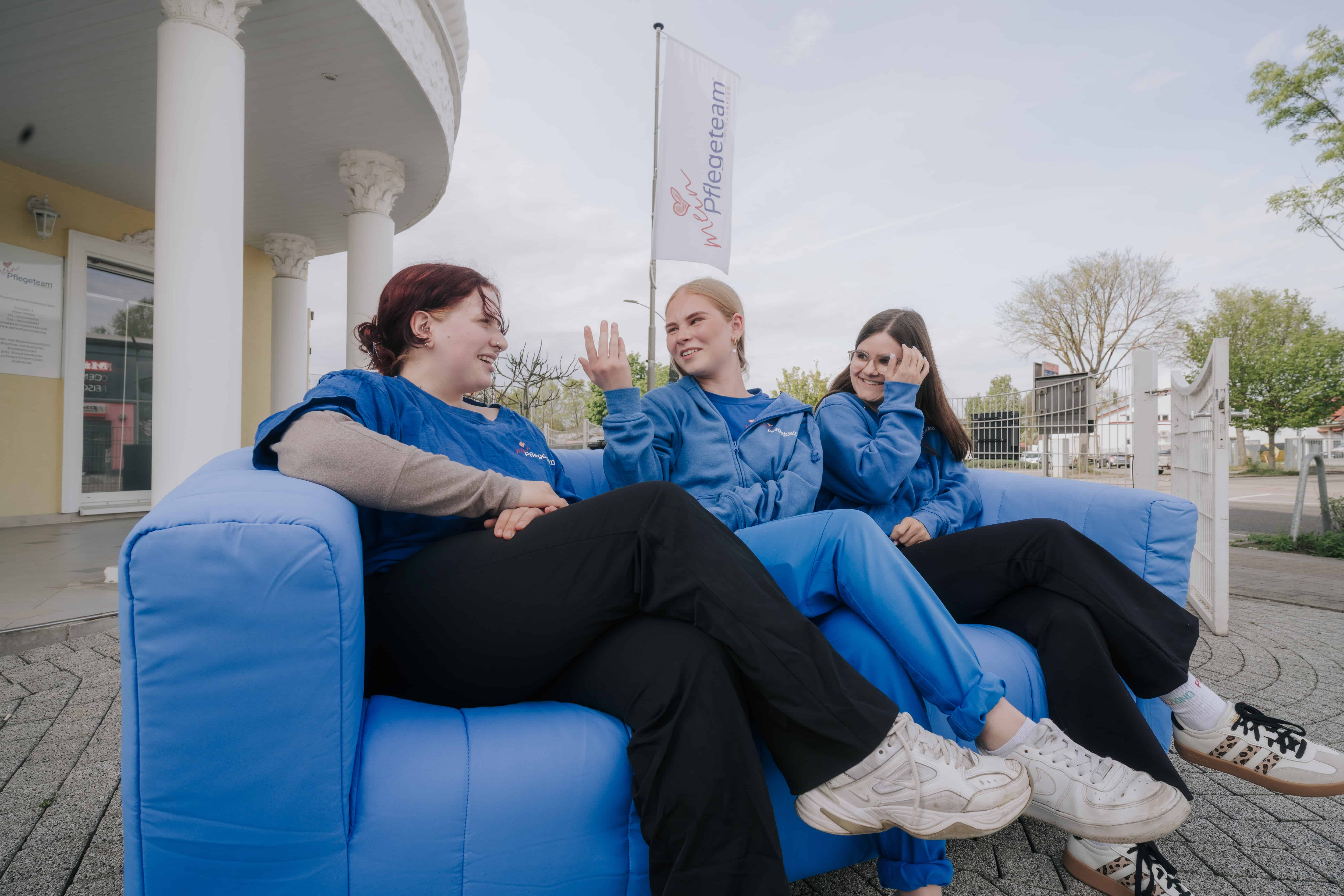 Drei Mitarbeiterinnen eines Pflegeteams sitzen gemeinsam im Freien und unterhalten sich in entspannter Atmosphäre. Das Bild steht für authentischen Social Media Content, Arbeitgeberkommunikation und Mitarbeitergewinnung in der Pflege.