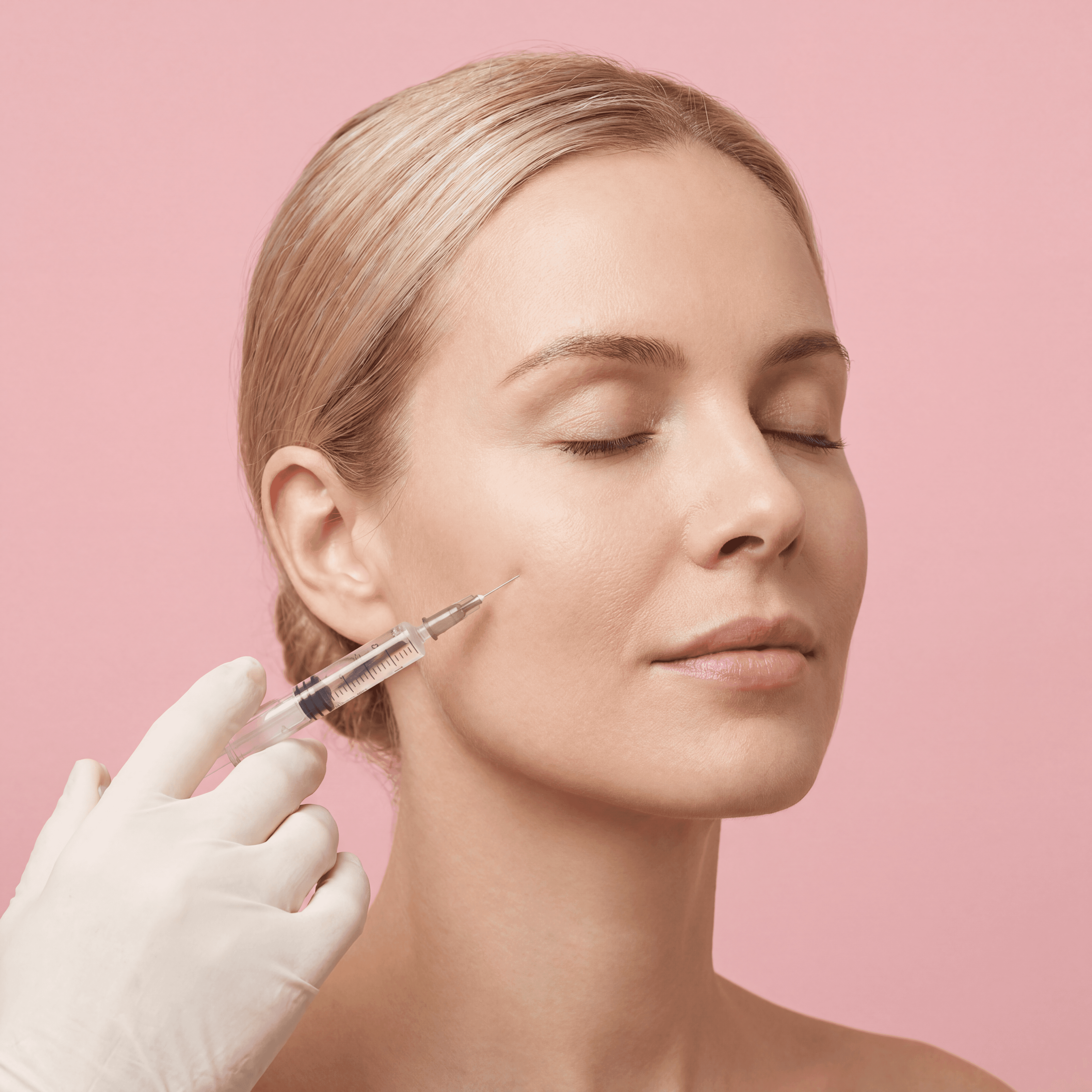 Blonde vrouw krijgt een injectie met filler in de wang tegen een roze achtergrond