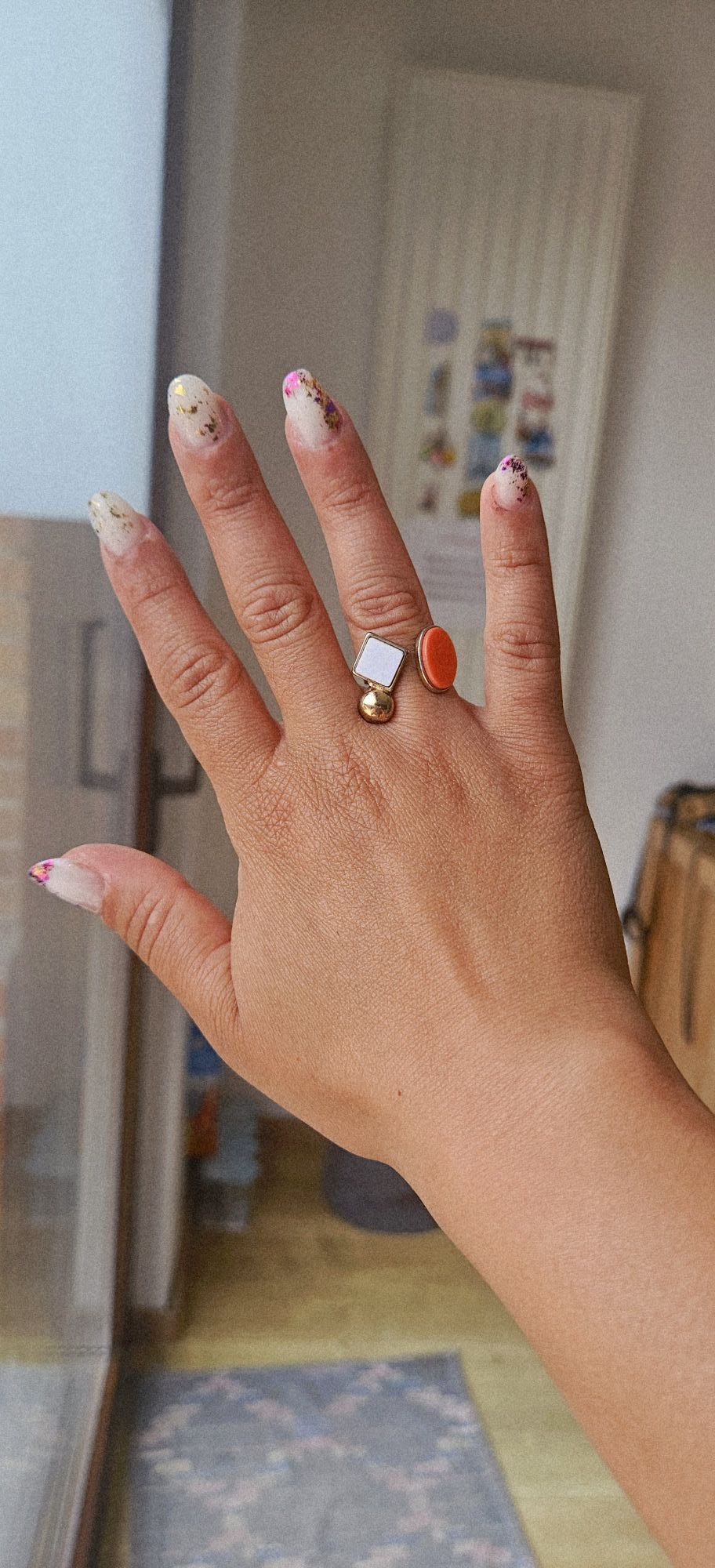 Hand with pink swirl nails and rings in car