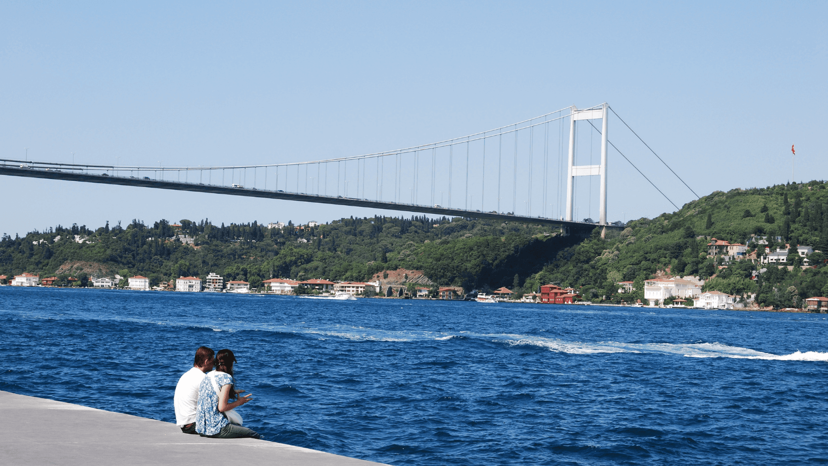 Couple by the Bosphorus Bridge in Istanbul, Türkiye on a sunny day