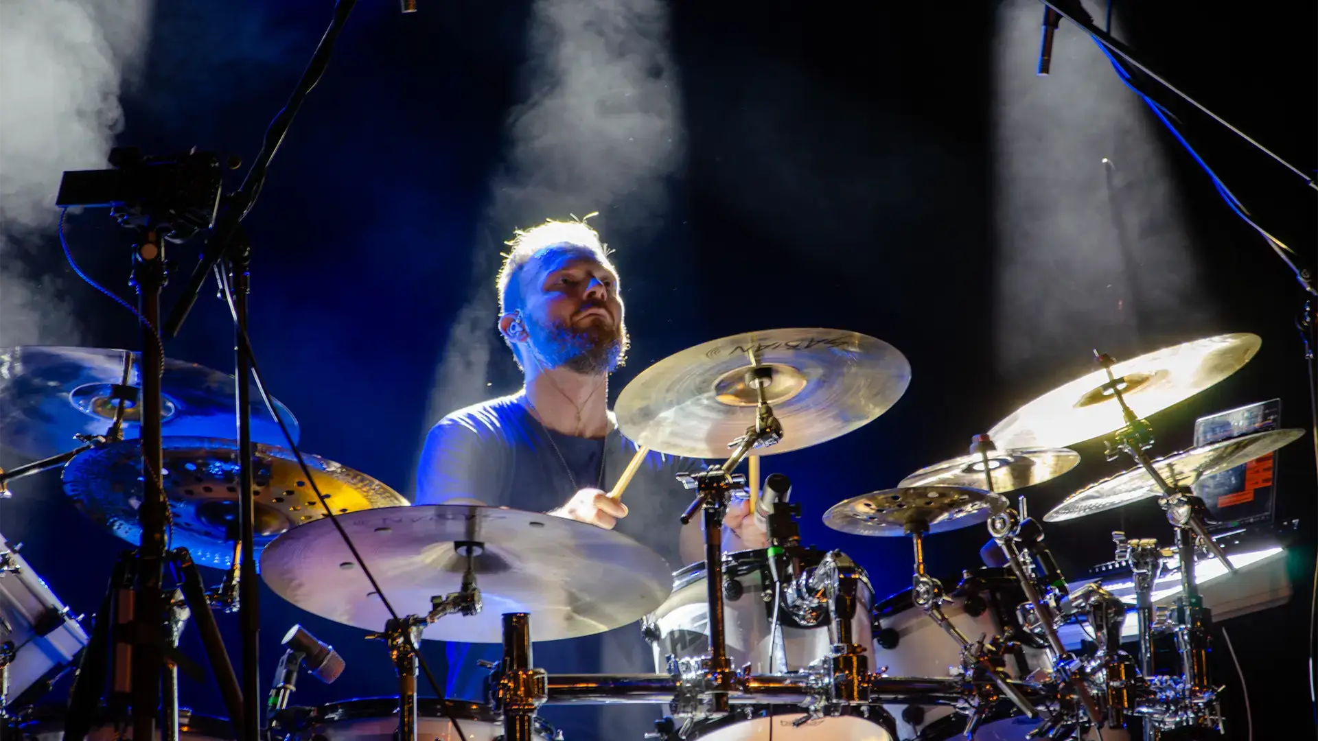 Bubeník v modrém světle reflektorů. Živé hudební ztvárnění energie a emocí spojených s vodou.