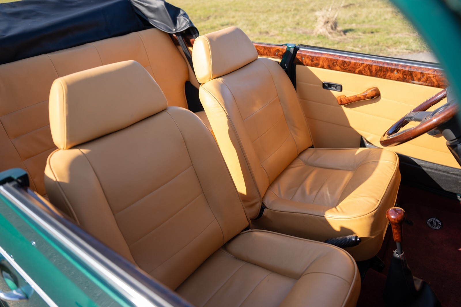 Interior view of a car showing tan leather seats with a convertible top, highlighting a warm and inviting atmosphere.