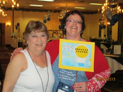 Shelley holding her “Dream Big” page beside a friend at a crop