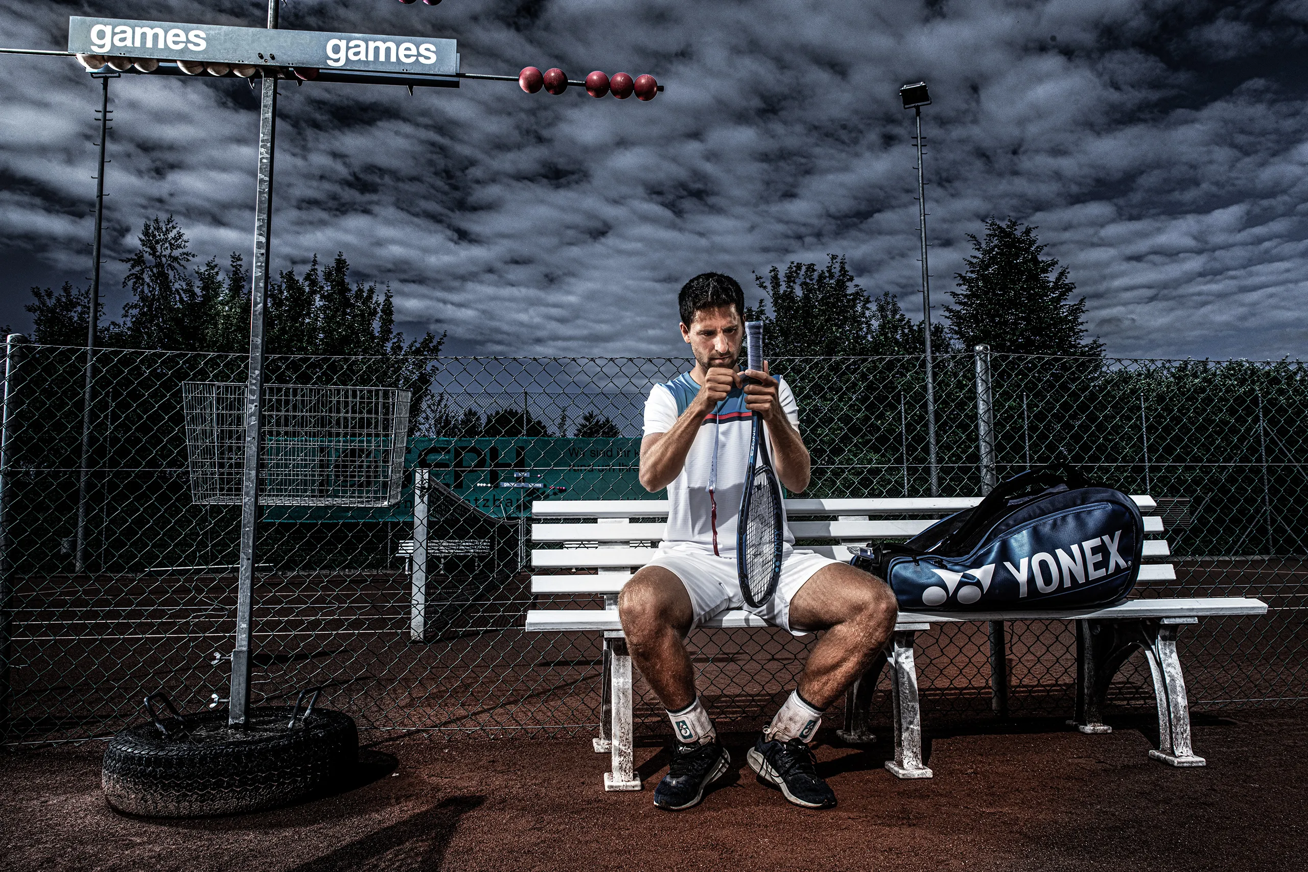 h_cinematic_mood	A thoughtful portrait of a male tennis player sitting on a bench with a dark dramatic sky and athletic gear.