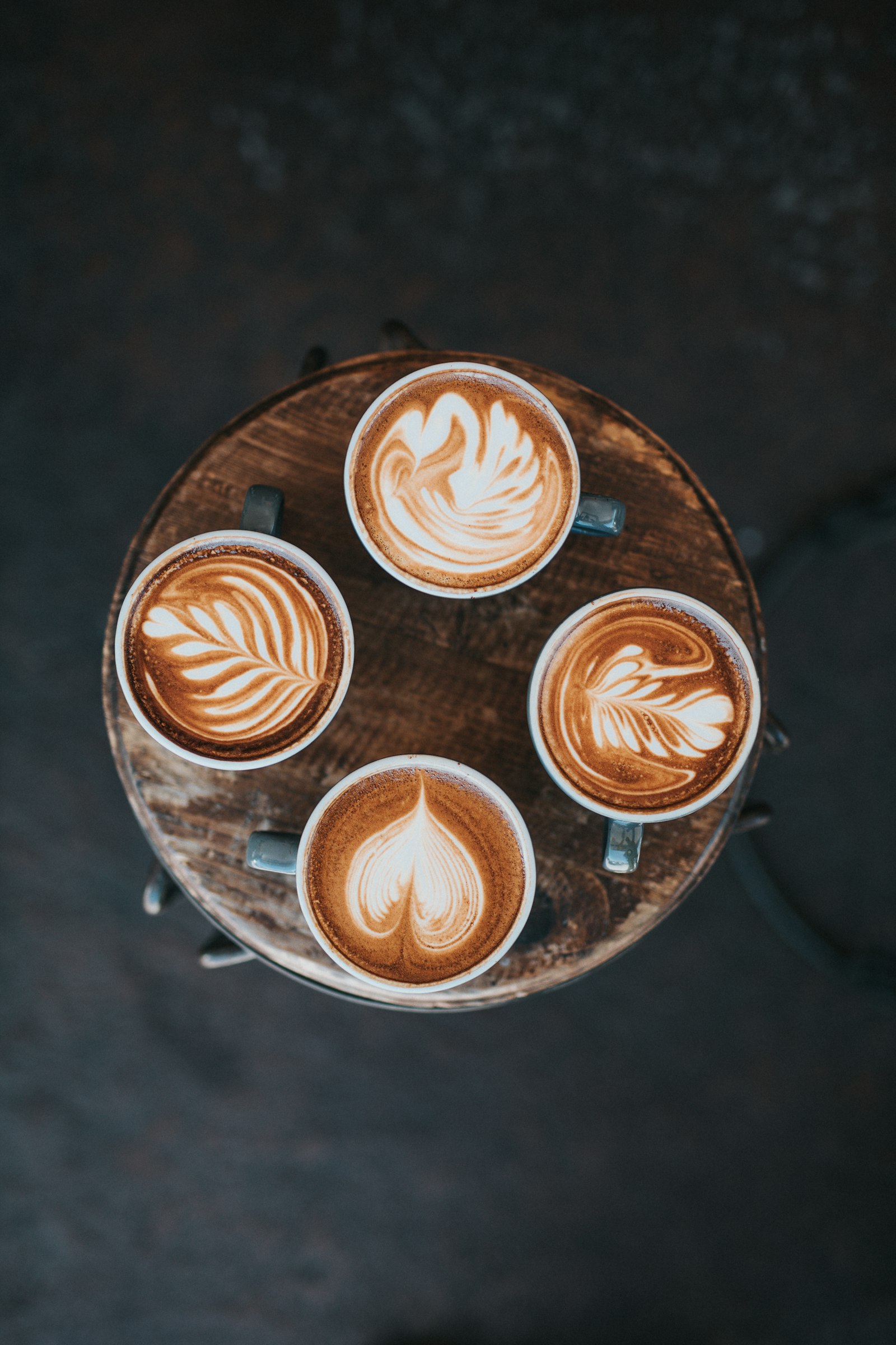 Vista aérea de una taza de café latte con arte sobre una mesa de madera