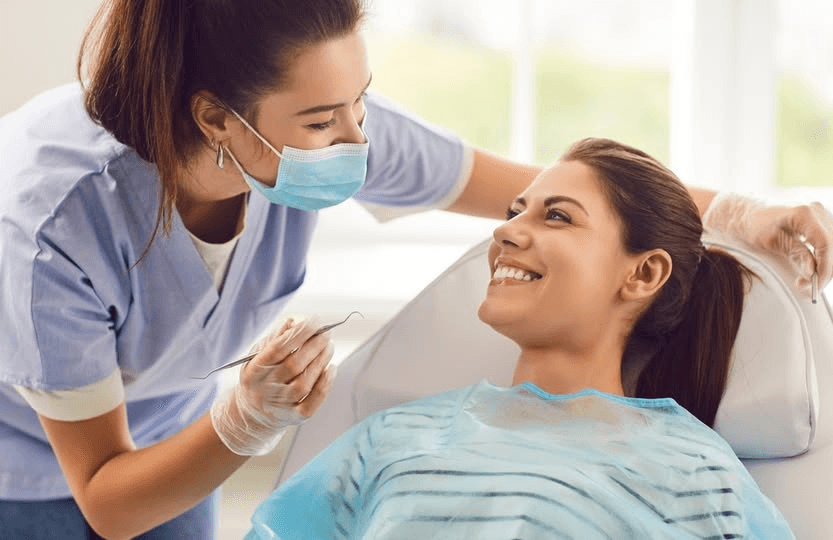 dentist in clinical setting, smiling with patient, confident