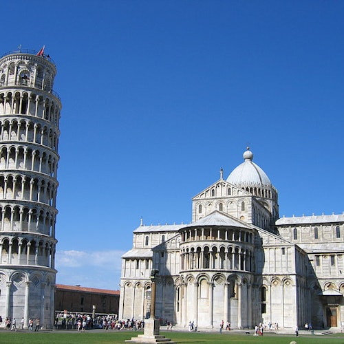 Torre di Pisa e Cattedrale di Pisa con turisti in una giornata di sole sotto un cielo azzurro limpido.
