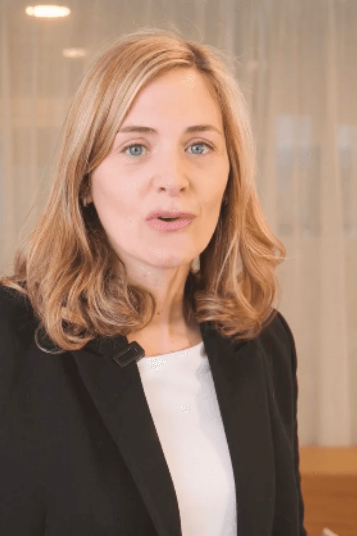 Young man in a formal outfit with a striped shirt, grey tie, and black coat. The tone is serious and professional, emphasizing subdued elegance.