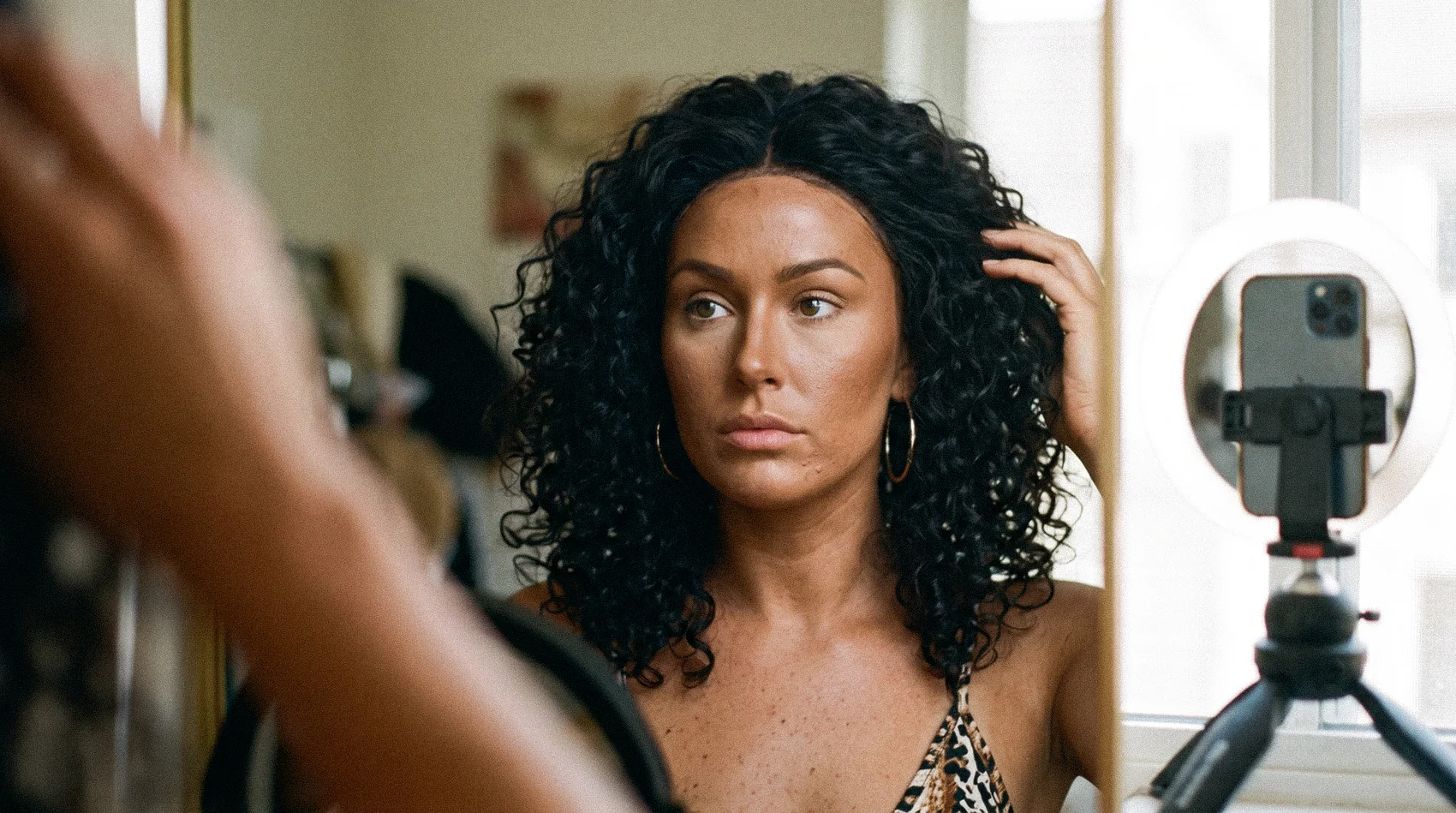 Influencer with curly wig and darkened makeup filming with ring light - what is blackfishing is the ad authentic example