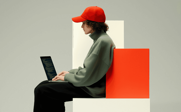 Boy using laptop while wearing red cap