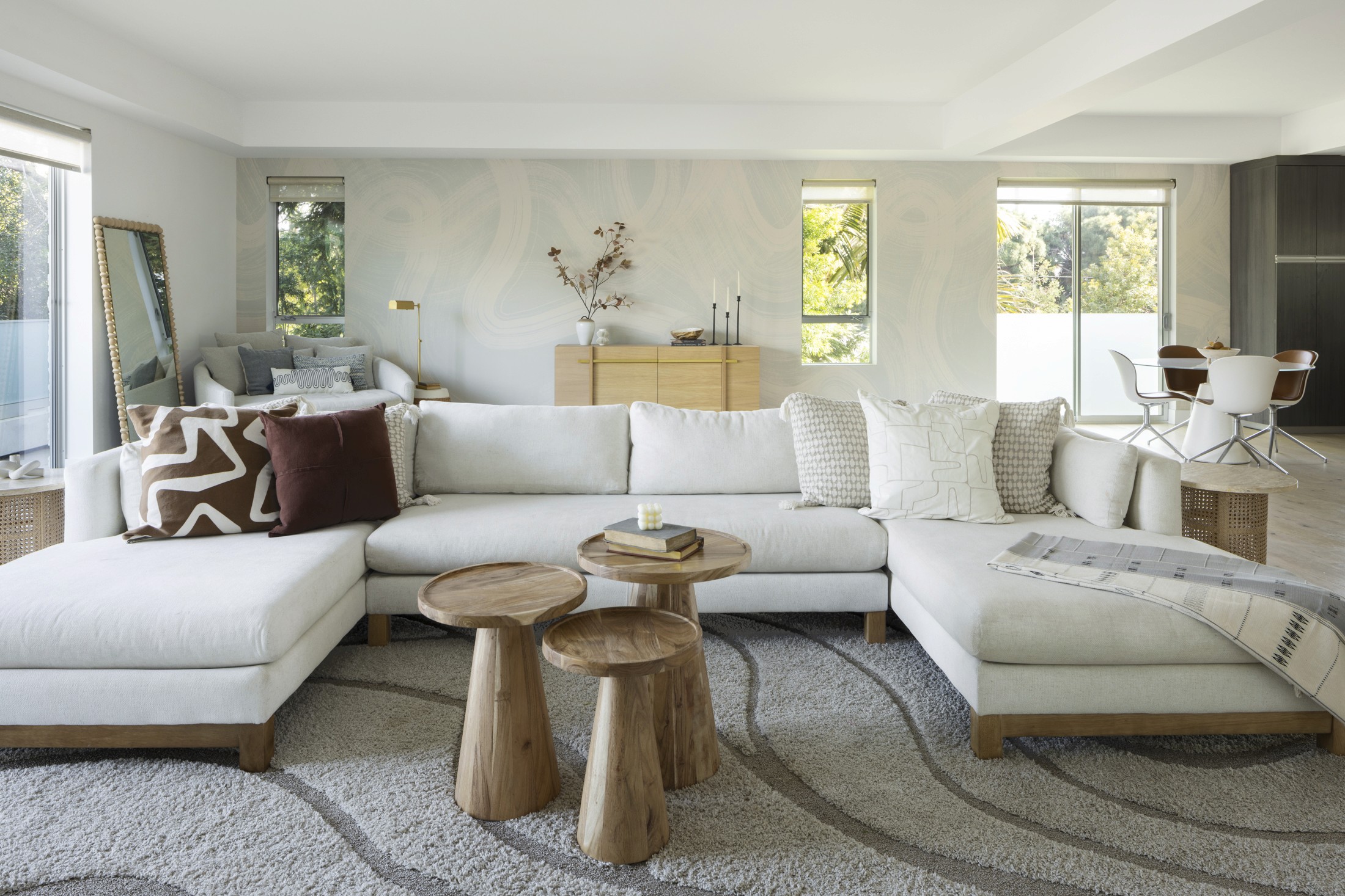 Bright living room with large white sectional, large area rug, console table in background, and tired coffee table in foreground
