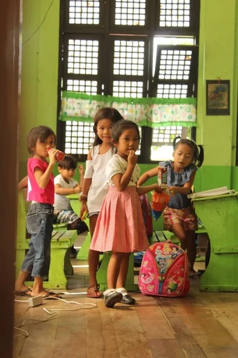 A group of Vietnamese children standing in a hallway looking at the camera