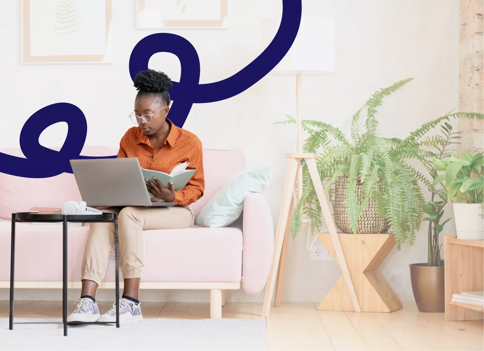 woman sitting on sofa holding laptop and notebook