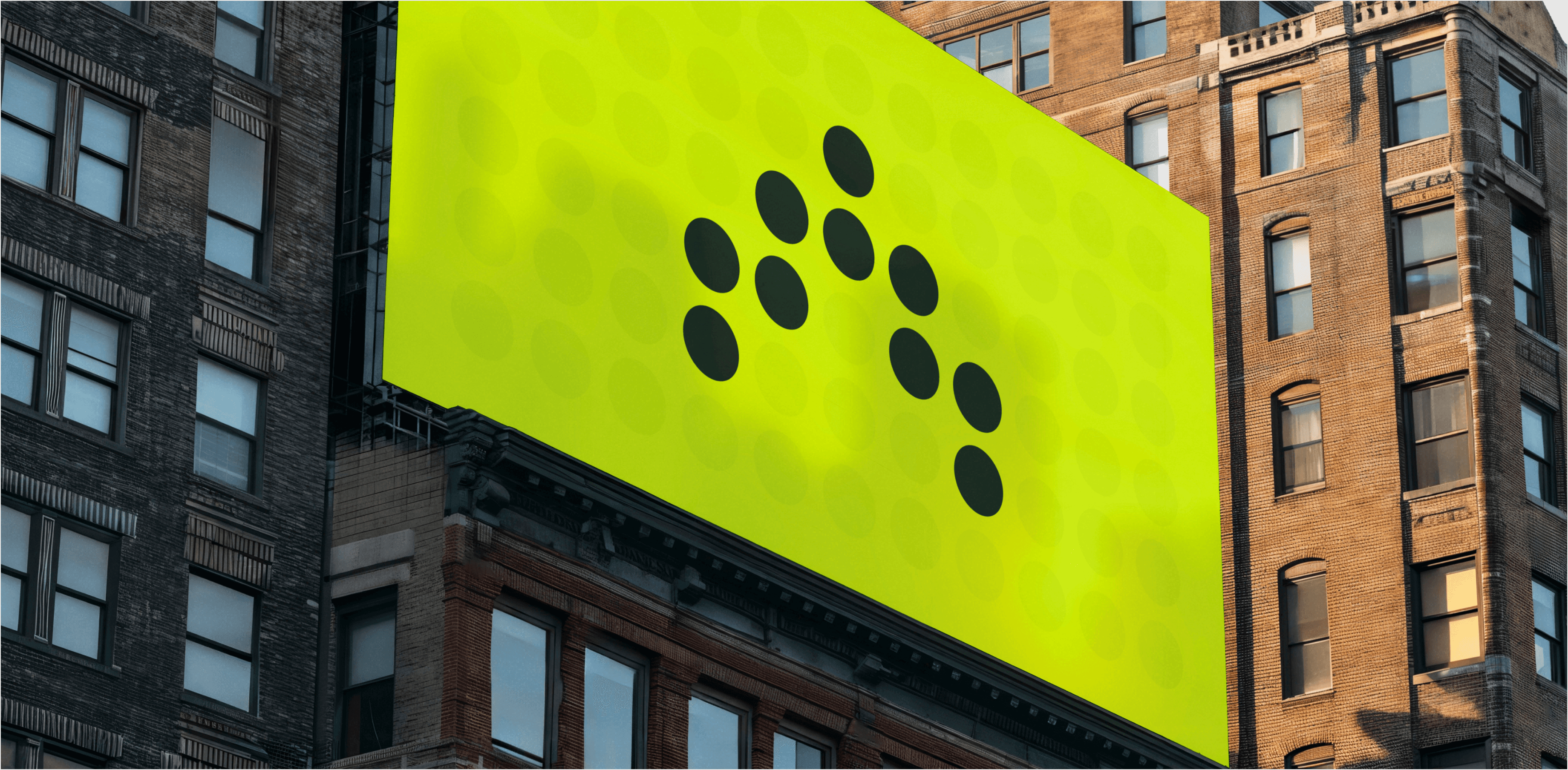 A large, bright green billboard with a minimalist design featuring black dots arranged in a pattern, displayed on the side of a tall urban building. The billboard stands out against the surrounding brick and concrete structures, with windows and architectural details visible.