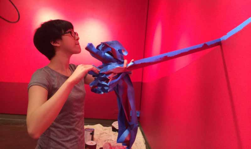 a student peeling off tape on the wall