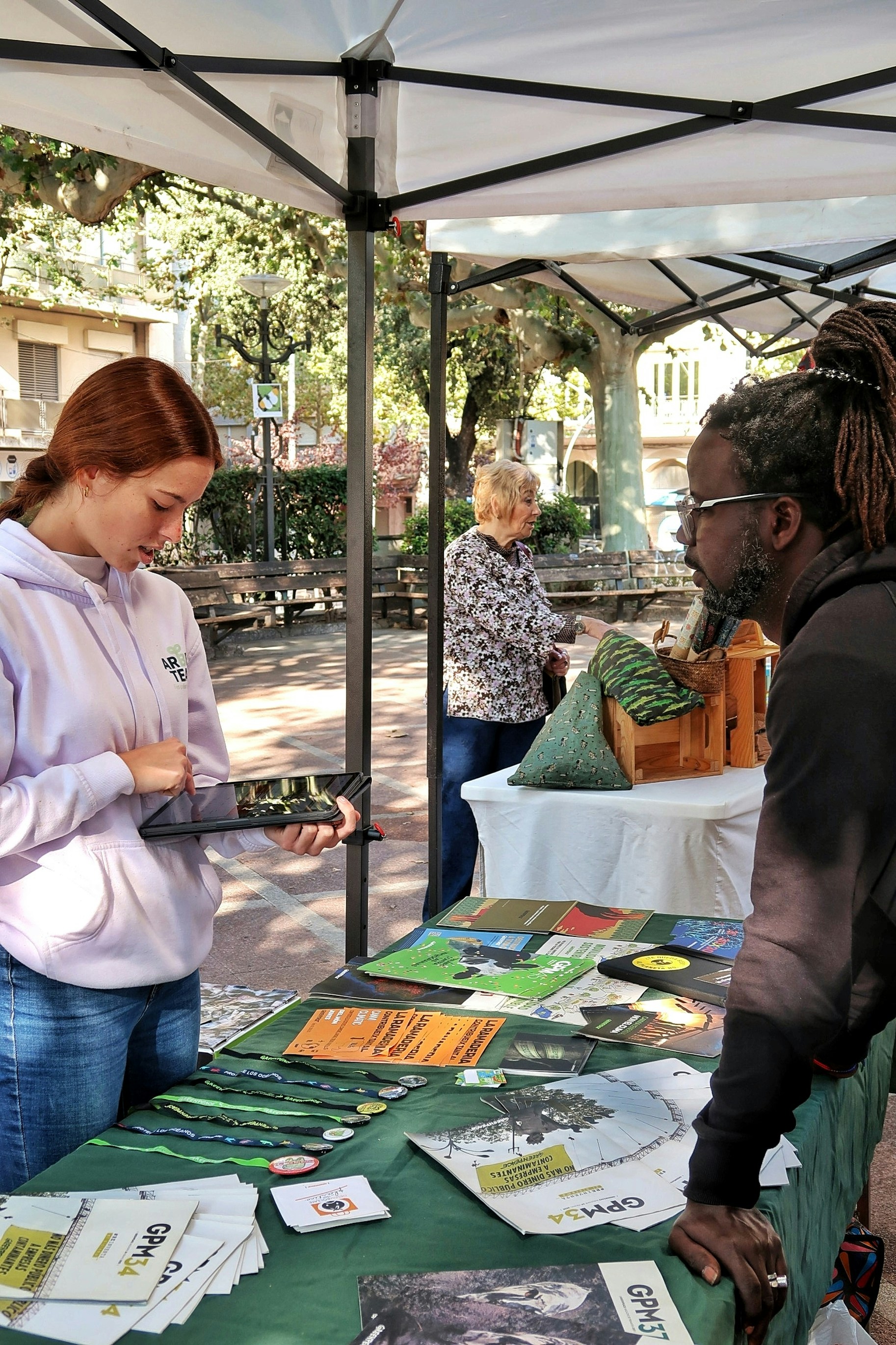People at an outdoor information booth with displayed materials.
