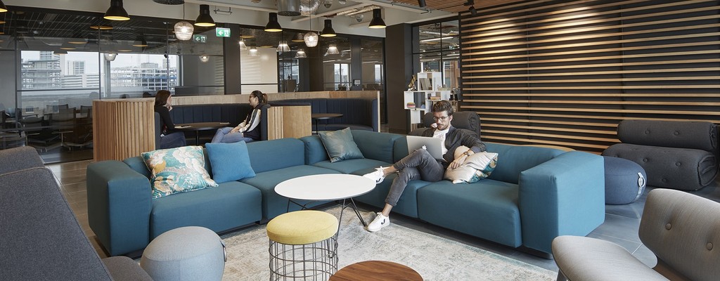 A sofa area based in the Havas UK London office - a few employees are sitting and working and having meetings