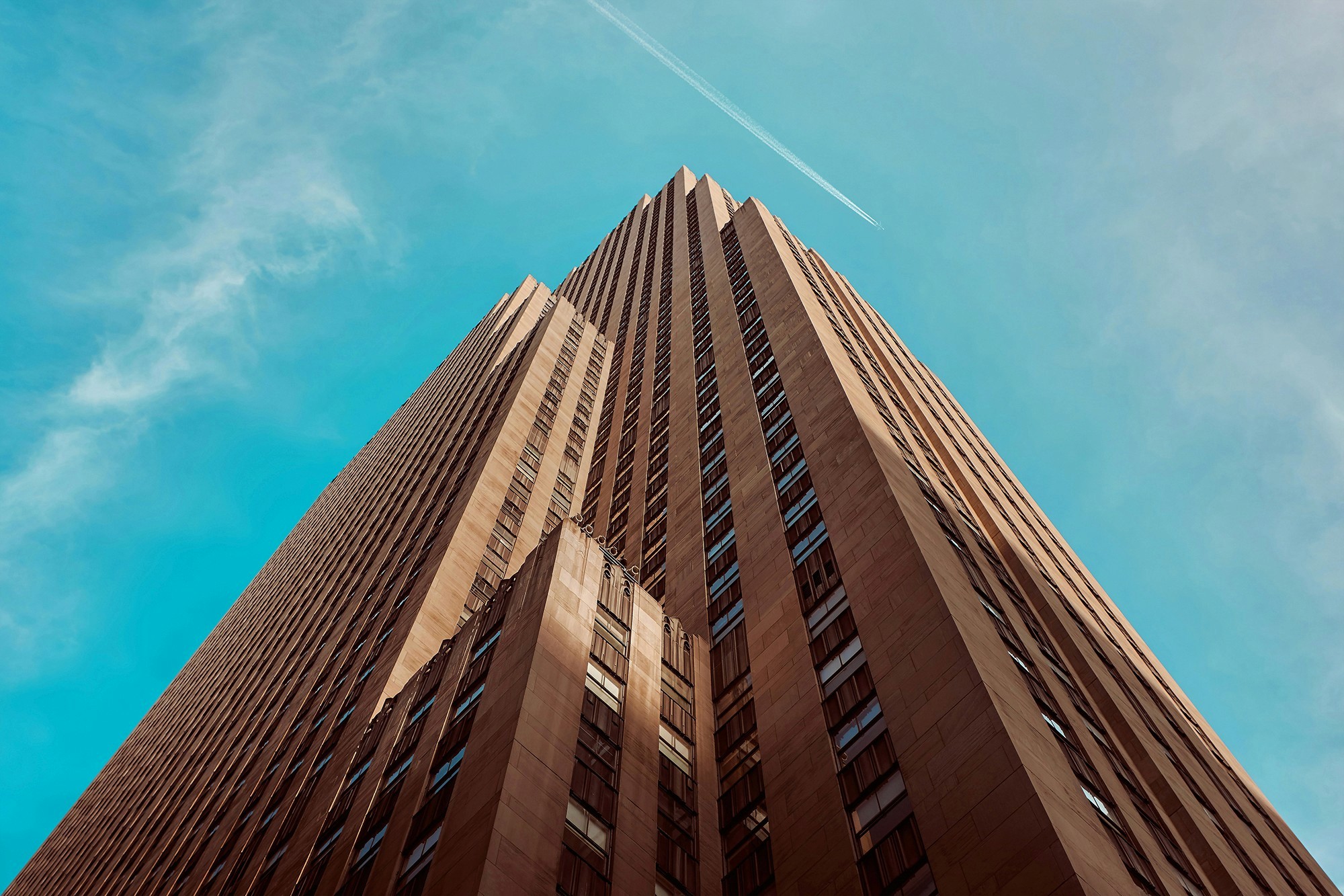 Looking up at a tall building against a blue sky with soft clouds, emphasizing its impressive height.