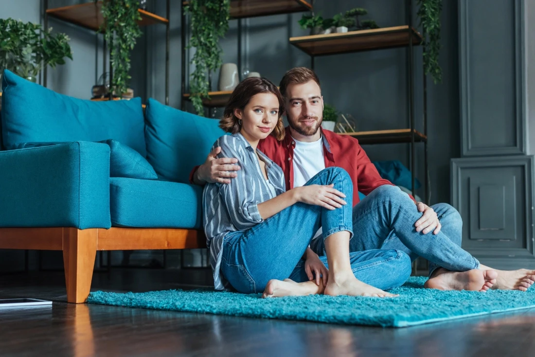 Couple sitting on floor embracing smiling at the camera