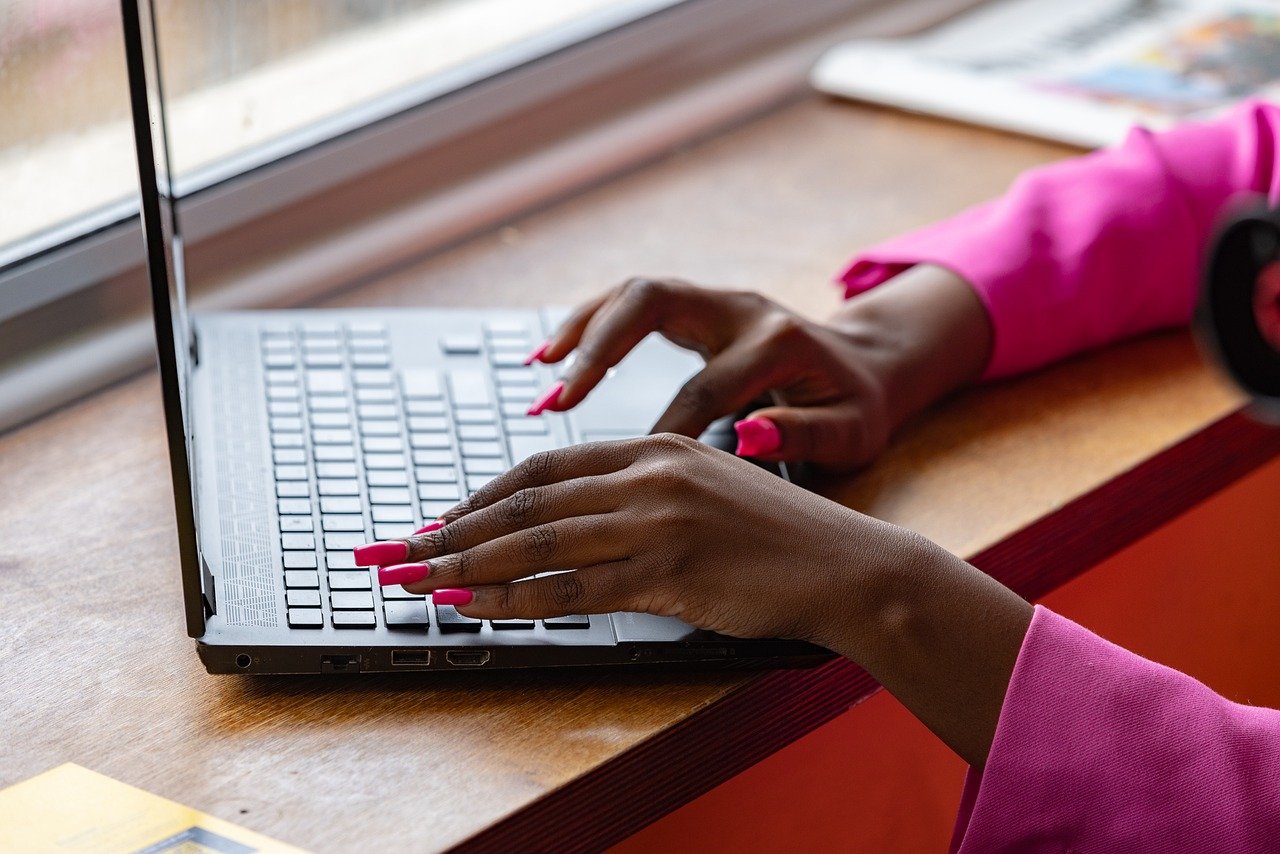 A woman typing on a laptop on a desk