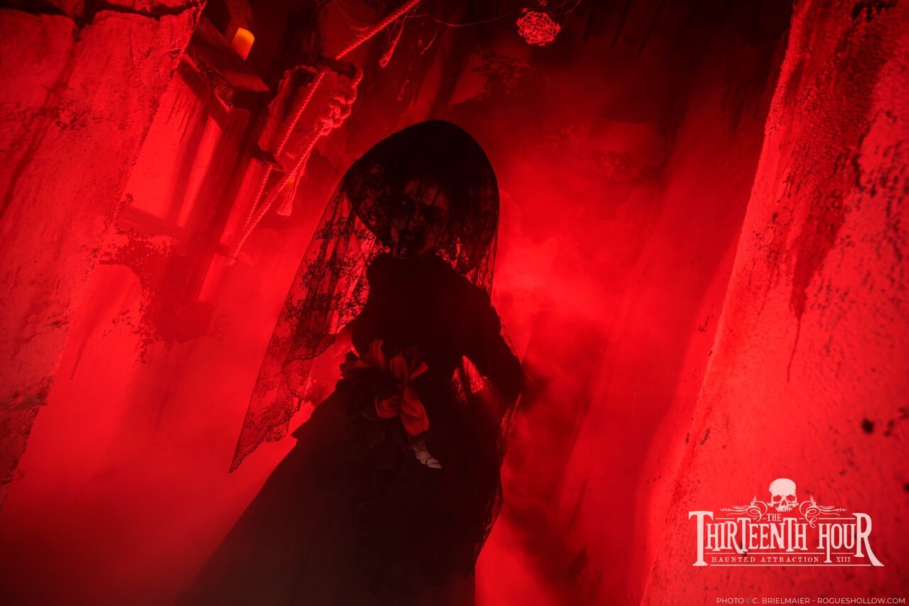 Veiled figure in a red fog-filled haunted house hallway