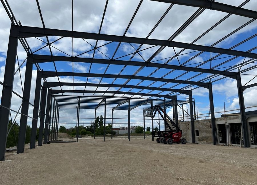 Structure métallique d’un bâtiment en cours de montage avec ciel dégagé en arrière-plan.