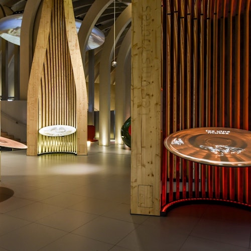 A modern museum exhibit with wooden structures and illuminated circular displays in a dimly lit room.