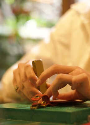 A close-up of hands using a tool to work on a leather piece, focusing on the precision required in a leather crafting workshop in Istanbul.