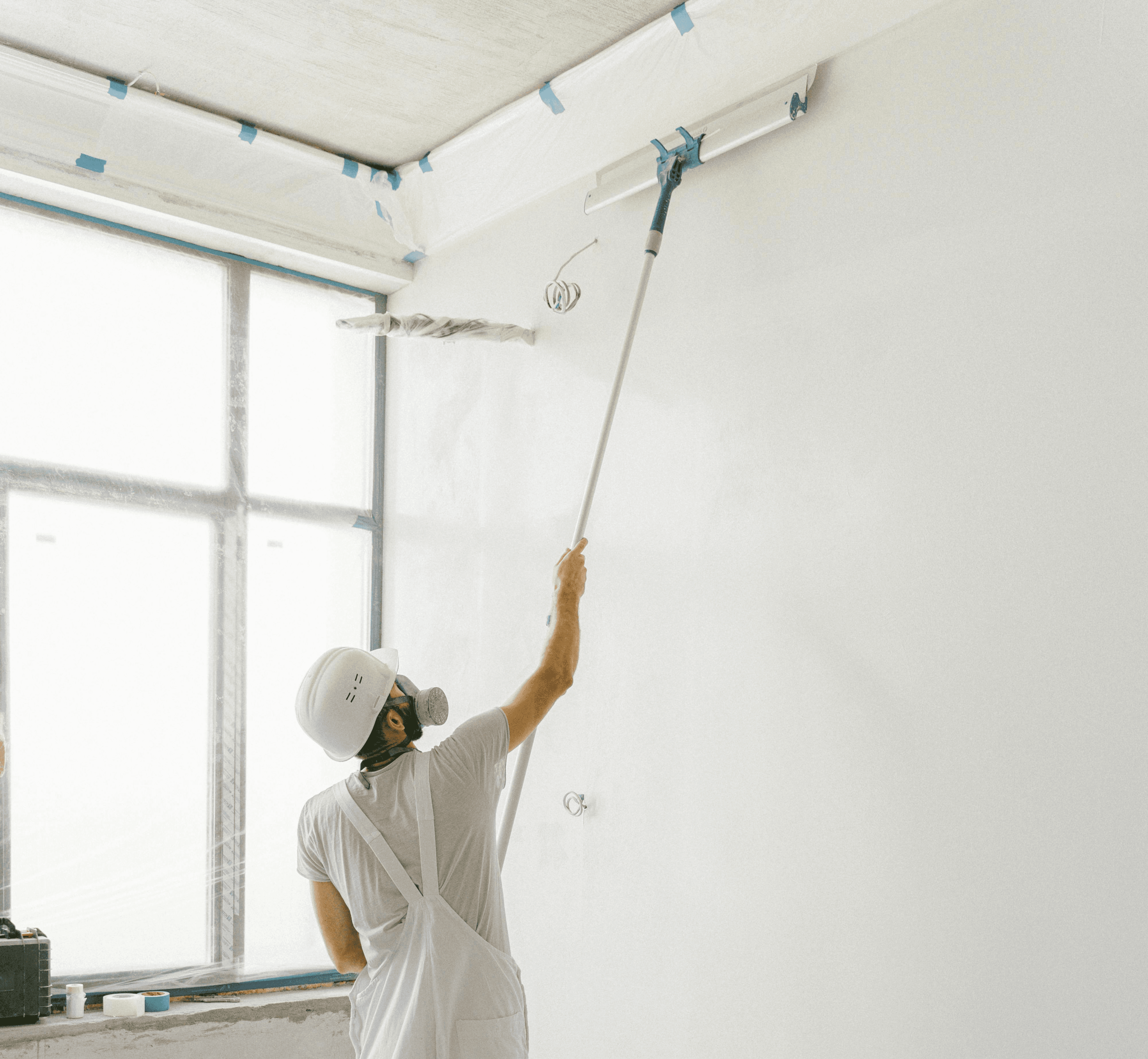a man painting a wall with a paint roller
