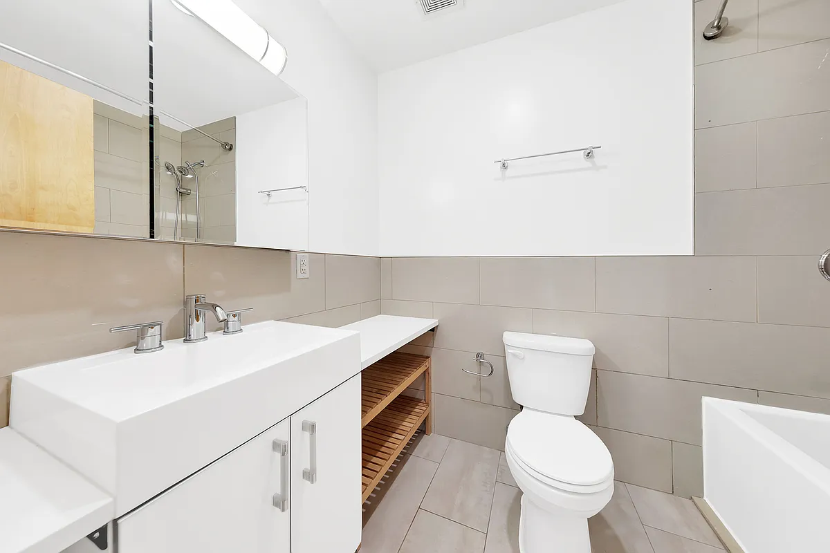 A bathroom featuring a toilet, sink, and shower, designed for functional and comfortable use.